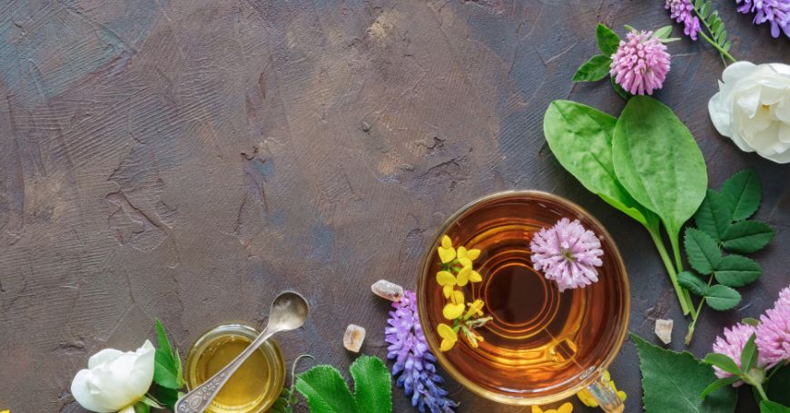 cup of herbal tea for colitis surrounded by flowers and leaves